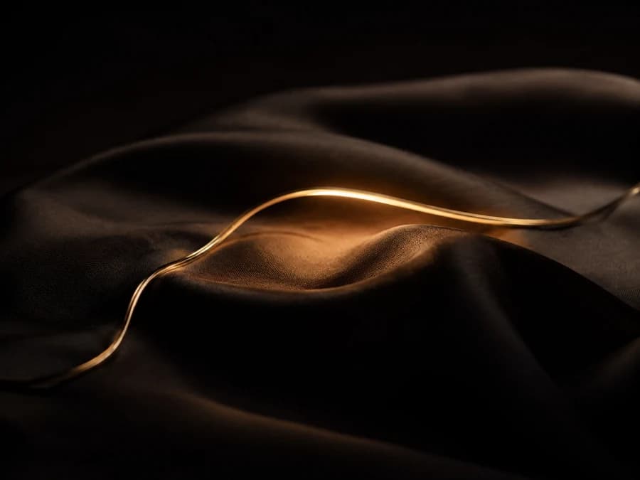 One warm golden thread of light resting calmly in folds of dark fabric